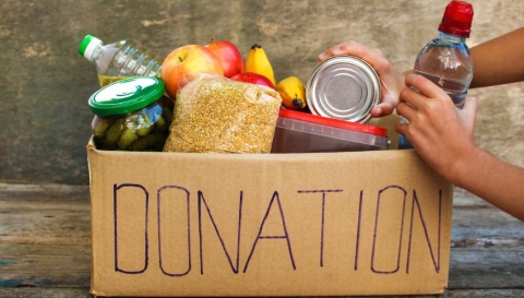 picture of a hand putting food in a donation box