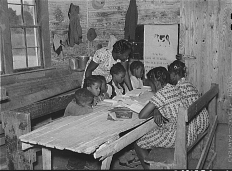 black and white picture of a woman teaching children at a kitchen table in the 1960's