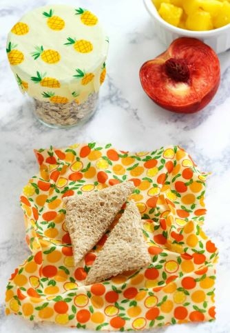 phot of a sandwich, glass, and half a nectarine sitting on a beeswax wrap