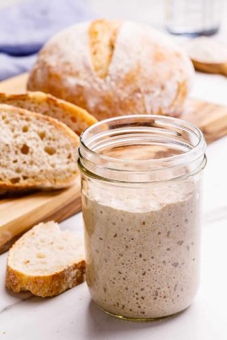 photo of a jar of sourdough starter and baked bread