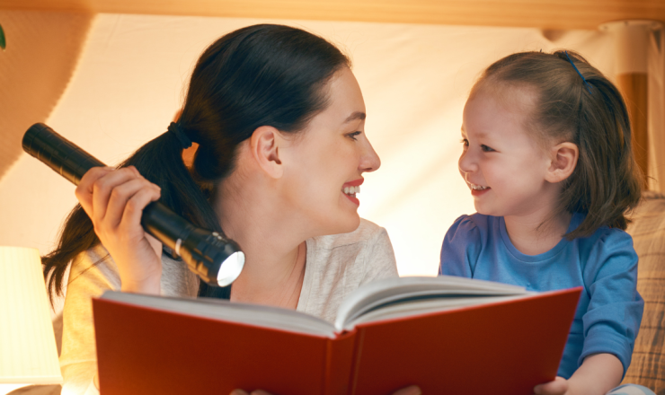 Mother and child reading with flashlight